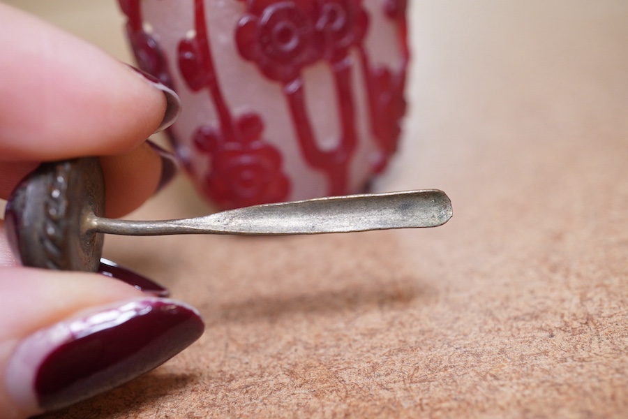 A Chinese cameo carved red overlaid on white snowflake ground snuff bottle and stopper, 19th century, 8cm high. Condition - small splinter chip to base, otherwise good